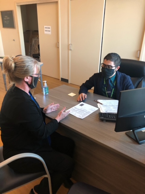 Principal Huerta at desk meeting with staff member
