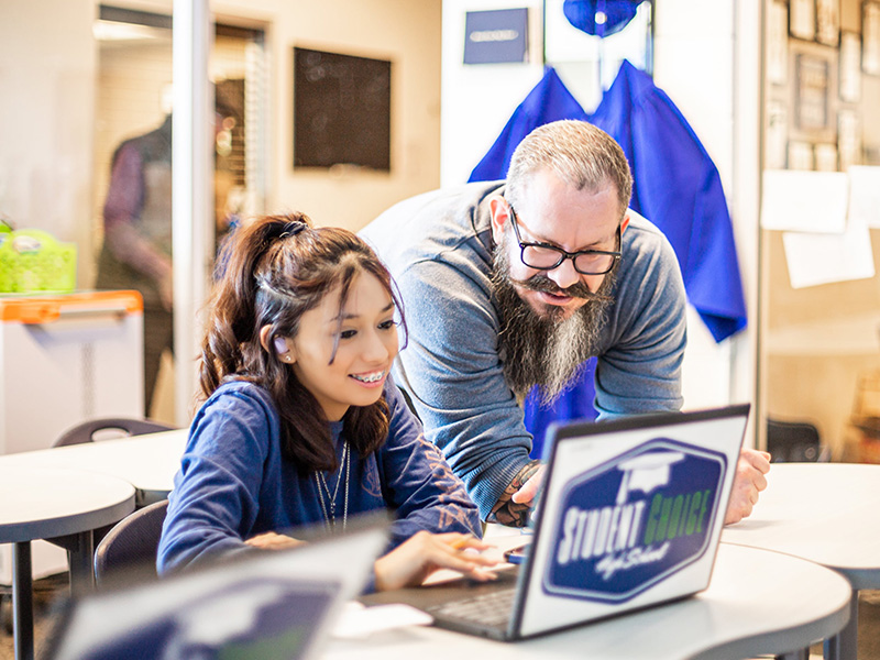 Student and staff looking at laptop-